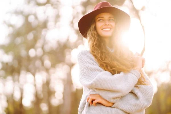 Stylish woman in sweater and hat enjoys autumn nature. People, freedom, lifestyle, travel and vacations concept.