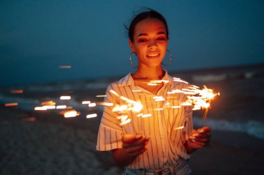 Ellerinde pırıl pırıl parlıyor. Doğada Noel havai fişeği ve gökyüzü arka planında ışık saçan kadınlar. Tatil, tatil, rahatlama ve yaşam tarzı konsepti.
