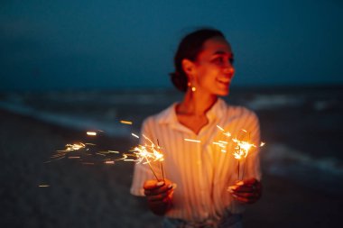 Ellerinde pırıl pırıl parlıyor. Doğada Noel havai fişeği ve gökyüzü arka planında ışık saçan kadınlar. Tatil, tatil, rahatlama ve yaşam tarzı konsepti.