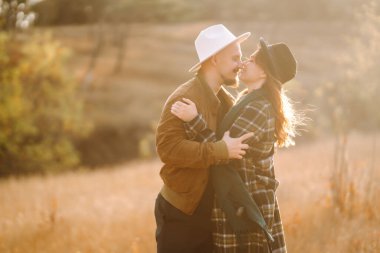 Güzel hippi çift sonbahar parkında eğleniyor. Güzel bir sonbahar günü. Genç çift dışarıda yürüyor ve sarılıyor, gençlik, aşk ve yaşam tarzı kavramı.