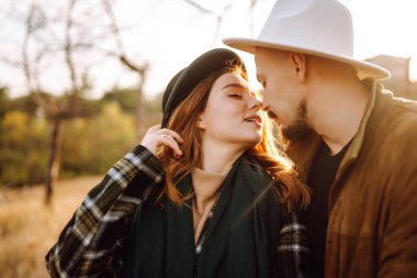 Güzel hippi çift sonbahar parkında eğleniyor. Güzel bir sonbahar günü. Genç çift dışarıda yürüyor ve sarılıyor, gençlik, aşk ve yaşam tarzı kavramı.
