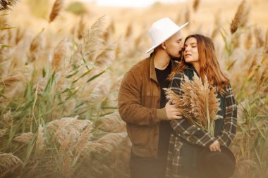 Güzel hippi çift sonbahar parkında eğleniyor. Güzel bir sonbahar günü. Genç çift dışarıda yürüyor ve sarılıyor, gençlik, aşk ve yaşam tarzı kavramı.