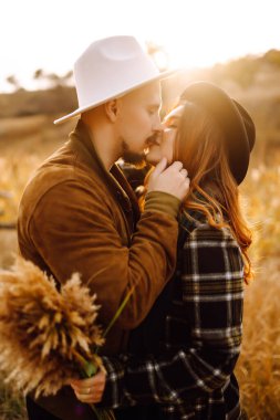 Güzel hippi çift sonbahar parkında eğleniyor. Güzel bir sonbahar günü. Genç çift dışarıda yürüyor ve sarılıyor, gençlik, aşk ve yaşam tarzı kavramı.