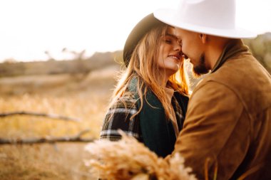 Güzel hippi çift sonbahar parkında eğleniyor. Güzel bir sonbahar günü. Genç çift dışarıda yürüyor ve sarılıyor, gençlik, aşk ve yaşam tarzı kavramı.
