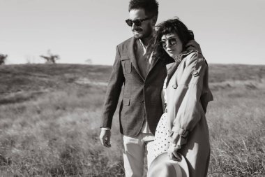 Genç bir çift güneşli bir günde dışarıda yürüyorlar. Adam nazikçe kadına sarılıyor. Aşk hikayesi. Sonbahar stili.