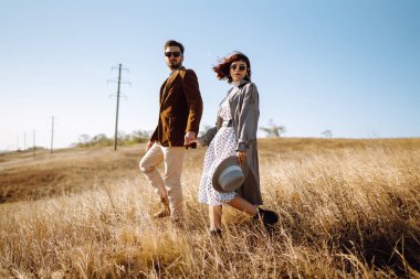 Genç bir çift güneşli bir günde dışarıda yürüyorlar. Adam nazikçe kadına sarılıyor. Aşk hikayesi. Sonbahar stili.