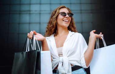 Alışveriş yapan bir kadın. Alışveriş yaptıktan sonra şehirde dolaşan alışveriş çantalı bir kadın. Kara Cuma, satış, tüketici, yaşam tarzı konsepti.