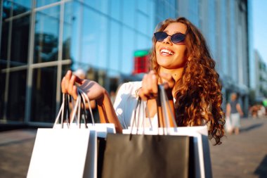 Alışveriş yapan bir kadın. Alışveriş yaptıktan sonra şehirde dolaşan alışveriş çantalı bir kadın. Kara Cuma, satış, tüketici, yaşam tarzı konsepti.