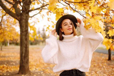 Parkta gezen, şık şapkalı genç bir kadının güneşli bir hayat tarzı portresi. Moda, tarz kavramı. İnsanlar, rahatlama ve tatil kavramı.