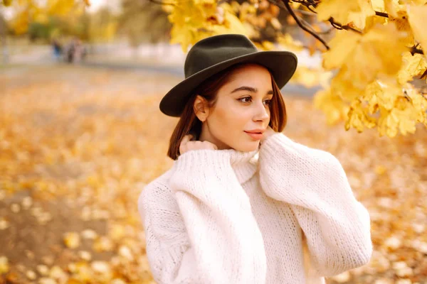 Parkta gezen, şık şapkalı genç bir kadının güneşli bir hayat tarzı portresi. Moda, tarz kavramı. İnsanlar, rahatlama ve tatil kavramı.