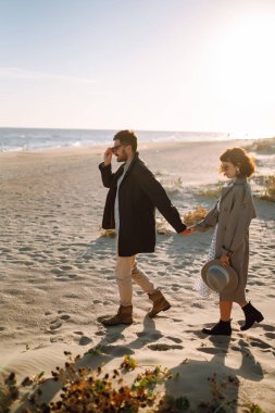 Moda çifti, sonbahar güneşli günlerinde sahilde eğleniyor. Seyahat, hafta sonu, rahatlama ve yaşam tarzı konsepti.. 