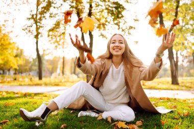 Doğada dinlenen genç bir kadın. İnsanlar, rahatlama ve tatil konsepti. Sonbahar stili.