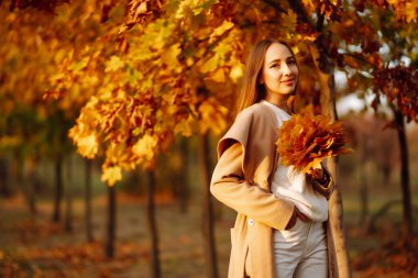 Doğada dinlenen genç bir kadın. İnsanlar, rahatlama ve tatil konsepti. Sonbahar stili.