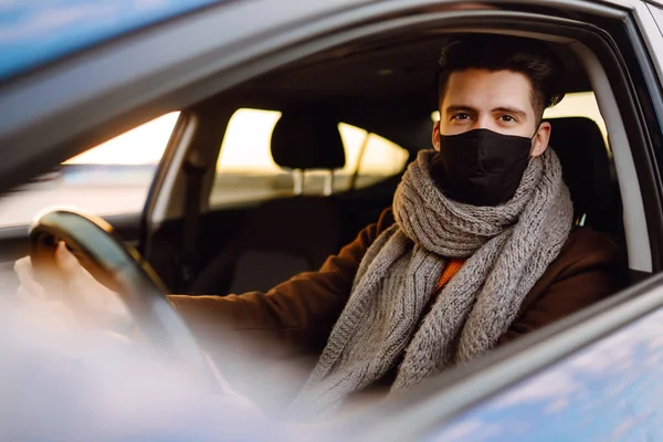 流行の間に医療用マスクに身を包んだ車を運転する男 マスクの運転手 ウイルスからの保護 輸送分離 Covid 2019 — ストック写真