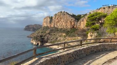 Sakin bir deniz manzaralı engebeli uçurumların altında kumlu bir sahil var. Bereketli yeşillik huzurlu bir öğleden sonra boyunca sakin atmosfere katkı sağlar..