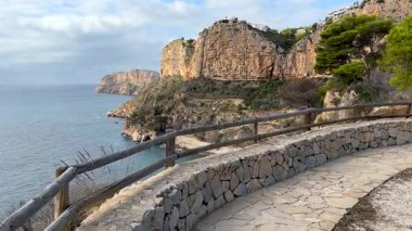 Sakin bir deniz manzaralı engebeli uçurumların altında kumlu bir sahil var. Bereketli yeşillik huzurlu bir öğleden sonra boyunca sakin atmosfere katkı sağlar..