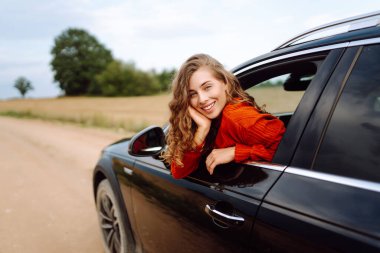 Neşeli kadın güneşli bir günde kendini özgür hissederek arabanın camından sarkıyor. Yolculukta olan genç bir kadın pencereden dışarı bakar ve esintiyi yakalar. Araba macerası, özgürlük ve rahatlama kavramı.