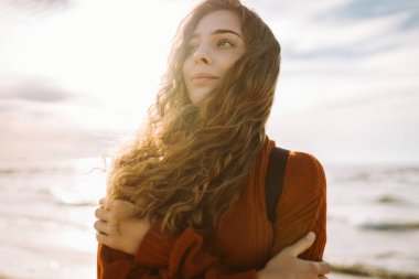 Sırt çantalı genç bir kadın kendini özgür hissediyor ve gün batımında deniz manzarasının tadını çıkarıyor. Güzel bir gezgin sahilde geziniyor. Özgürlük ve rahatlama kavramı.