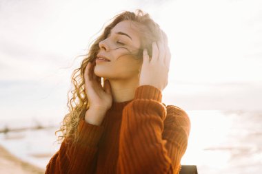 Sırt çantalı genç bir kadın kendini özgür hissediyor ve gün batımında deniz manzarasının tadını çıkarıyor. Güzel bir gezgin sahilde geziniyor. Özgürlük ve rahatlama kavramı.