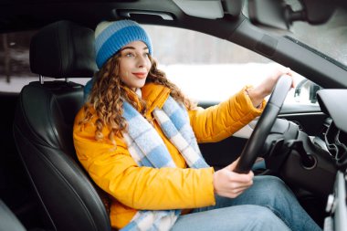 Karlı bir günde parlak sarı ceketli genç bir kadın araba kullanıyor. Güzel bir kadın soğuk bir kış gününde araba sürmekten hoşlanır. Ulaşım kavramı, keyif. Yaşam biçimi.