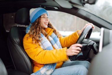 Karlı bir günde parlak sarı ceketli genç bir kadın araba kullanıyor. Güzel bir kadın soğuk bir kış gününde araba sürmekten hoşlanır. Ulaşım kavramı, keyif. Yaşam biçimi.