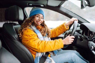 Karlı bir günde parlak sarı ceketli genç bir kadın araba kullanıyor. Güzel bir kadın soğuk bir kış gününde araba sürmekten hoşlanır. Ulaşım kavramı, keyif. Yaşam biçimi.