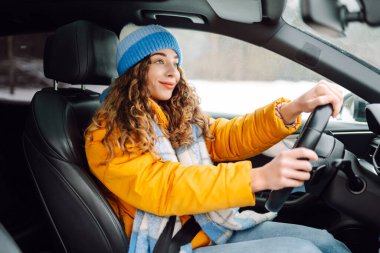 Karlı bir günde parlak sarı ceketli genç bir kadın araba kullanıyor. Güzel bir kadın soğuk bir kış gününde araba sürmekten hoşlanır. Ulaşım kavramı, keyif. Yaşam biçimi.