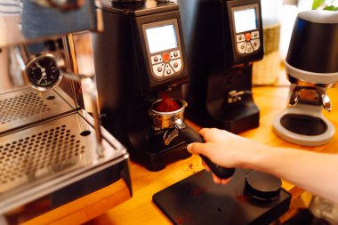 Deneyimli bir barista sıcak bir kafede taze demlenmiş kahve hazırlar. Genç bir kadın espressoya süt döker ve köpürür. Küçük iş konsepti, içecekler.