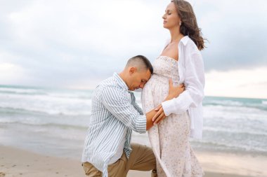 Çocuk bekleyen genç bir çift sahilde duruyor ve gün doğumunda deniz manzarasının tadını çıkarıyor. Hamile kadın ve kocası birlikte zaman geçiriyorlar. Aile, aşk ve doğa kavramları.