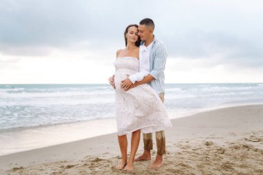 Çocuk bekleyen genç bir çift sahilde duruyor ve gün doğumunda deniz manzarasının tadını çıkarıyor. Hamile kadın ve kocası birlikte zaman geçiriyorlar. Aile, aşk ve doğa kavramları.