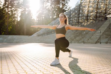 Formda bir kadın batan güneşin altında açık hava kortunda egzersiz yapıyor. Genç bir kadın antrenman yapar, atlar ya da dışarı çıkar. Konsept: Spor, açık hava. Etkin yaşam biçimi.