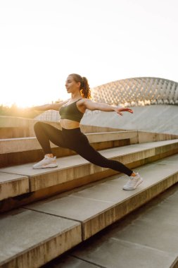 Formda bir kadın batan güneşin altında açık hava kortunda egzersiz yapıyor. Genç bir kadın antrenman yapar, atlar ya da dışarı çıkar. Konsept: Spor, açık hava. Etkin yaşam biçimi.