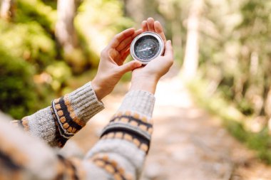 Sırt çantalı kadın yürüyüşçü kayalık yürüyüş yolunda pusula tutuyor. Dişinin arkadan görünüşü pusulaya bakar ve dağların doğal güzelliğinden zevk alır. Seyahat ve seyrüsefer kavramları. Etkin yaşam biçimi.