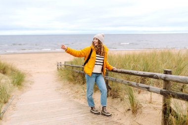 Parlak ceketli bir gezgin bulutlu bir günde kumlu bir plaj boyunca yürür. Güzel bir kadın dışarıda eğleniyor, deniz manzarasının tadını çıkarıyor. Konsept macera, eğlence ve özgürlük..