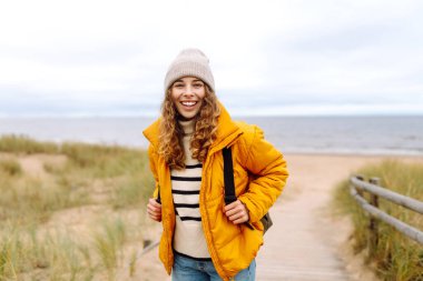 Parlak ceketli bir gezgin bulutlu bir günde kumlu bir plaj boyunca yürür. Güzel bir kadın dışarıda eğleniyor, deniz manzarasının tadını çıkarıyor. Konsept macera, eğlence ve özgürlük..