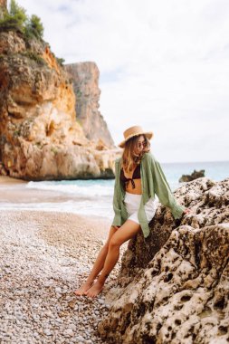 Kumsalda mutlu bir kadın deniz manzarasının tadını çıkarıyor. Hasır şapkalı genç bir kadın kendini özgür hissediyor. Sonsuz denize bakıyor. Özgürlük, doğa ve rahatlama kavramları.