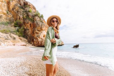 Kumsalda mutlu bir kadın deniz manzarasının tadını çıkarıyor. Hasır şapkalı genç bir kadın kendini özgür hissediyor. Sonsuz denize bakıyor. Özgürlük, doğa ve rahatlama kavramları.