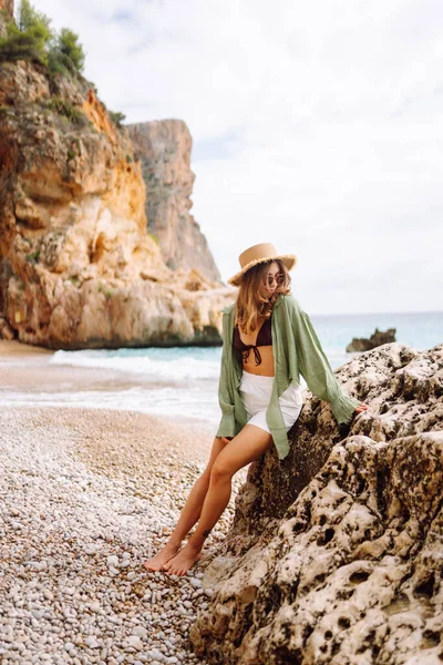 Kumsalda mutlu bir kadın deniz manzarasının tadını çıkarıyor. Hasır şapkalı genç bir kadın kendini özgür hissediyor. Sonsuz denize bakıyor. Özgürlük, doğa ve rahatlama kavramları.