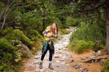 Sırt çantalı bir bayan yürüyüşçü gün batımında bir dağ zeminine karşı duruyor. Mutlu bir kadın yolculuğunda dağların ve kayalıkların tadını çıkarır. Macera, iz ve aktif yaşam tarzı kavramları.