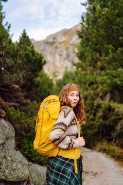 Sırt çantalı bir bayan yürüyüşçü gün batımında bir dağ zeminine karşı duruyor. Mutlu bir kadın yolculuğunda dağların ve kayalıkların tadını çıkarır. Macera, iz ve aktif yaşam tarzı kavramları.