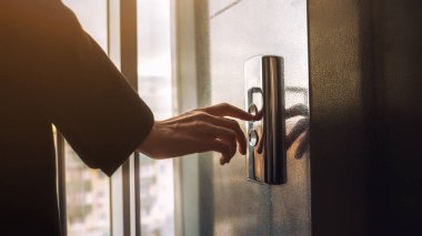 Yakın plan. Bir insan parmağı asansör düğmesine basar. Kapalı mekanda bir erkek eli. Kırmızı bir düğme. Teknoloji kavramı.