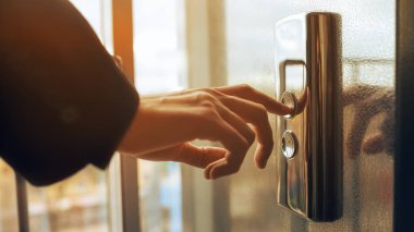 Yakın plan. Bir insan parmağı asansör düğmesine basar. Kapalı mekanda bir erkek eli. Kırmızı bir düğme. Teknoloji kavramı.