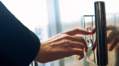 Yakın plan. Bir insan parmağı asansör düğmesine basar. Kapalı mekanda bir erkek eli. Kırmızı bir düğme. Teknoloji kavramı.