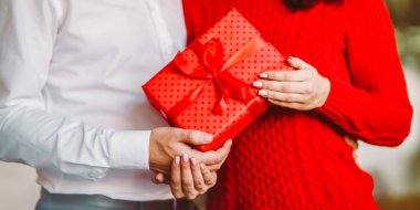 Adam karısına kırmızı kurdeleli bir hediye kutusu veriyor. Sevgililer Günü, tatil ve sürpriz konsept.