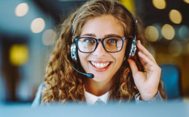 Çağrı merkezi ajanının kulaklığı modern ofiste yardım hattında çalışıyor. Video konferansı.