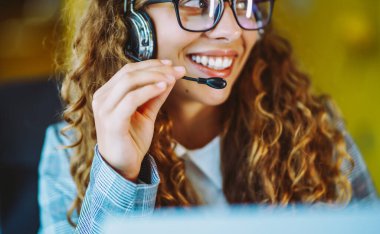 Çağrı merkezi ajanının kulaklığı modern ofiste yardım hattında çalışıyor. Video konferansı.