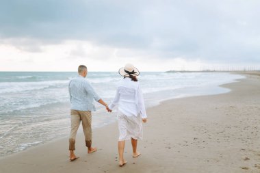 Bekleyen mutlu ebeveynler sahilde durup deniz manzarasının tadını çıkarıyorlar. Bir adam ve hamile karısı deniz kıyısında geziniyorlar. Aile kavramları, beklentiler ve sevgi..