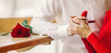 Aşık bir adam yüzük kutusunu tutar ve kız arkadaşına evlenme teklif eder. Genç bir çift yıldönümlerini bir kafede buluşarak kutluyor. Konsept: Tatil, aşkım. Sevgililer Günü.