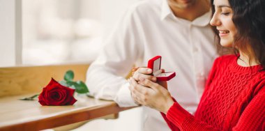 Aşık bir adam yüzük kutusunu tutar ve kız arkadaşına evlenme teklif eder. Genç bir çift yıldönümlerini bir kafede buluşarak kutluyor. Konsept: Tatil, aşkım. Sevgililer Günü.