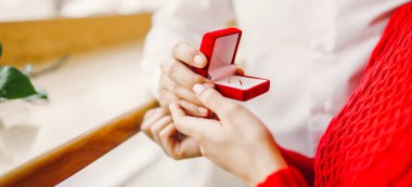 Aşık bir adam yüzük kutusunu tutar ve kız arkadaşına evlenme teklif eder. Genç bir çift yıldönümlerini bir kafede buluşarak kutluyor. Konsept: Tatil, aşkım. Sevgililer Günü.